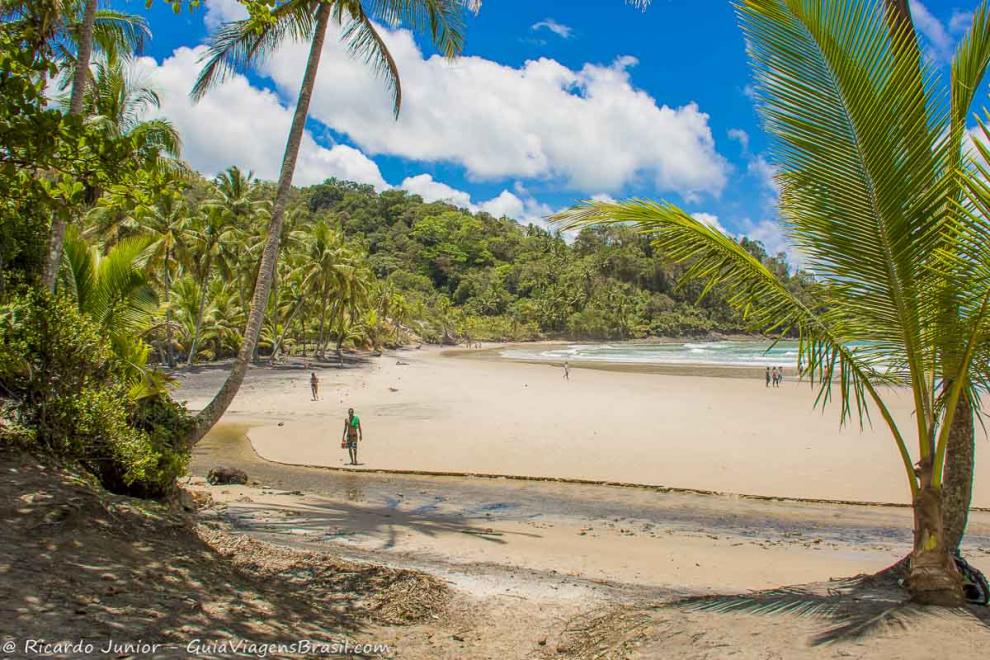 Imagem de algumas pessoas andando nas areias da Praia da Engenhoca.